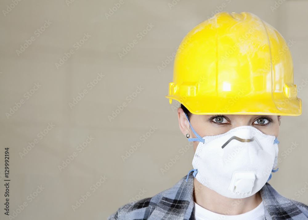 Portrait of female worker wearing dust mask and hardhat over colored background Portrait of female worker wearing dust mask and hardhat over colored background