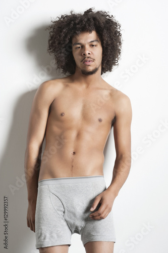 Portrait of young man in boxer shorts standing over white background