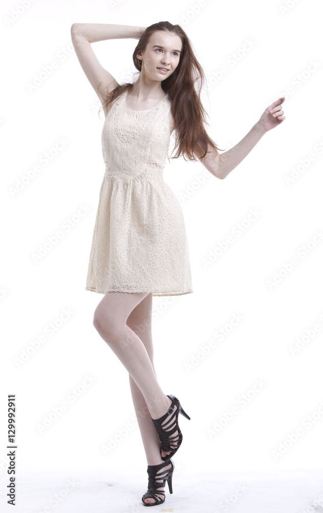 Beautiful young woman in dress with hand in her hair looking away against white background Beautiful young woman in dress with hand in her hair looking away against white background