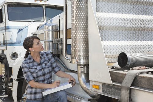 Fotografie Woman inspecting flatbed truck