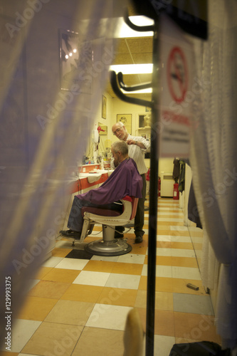 Barber giving a haircut to senior man in salon