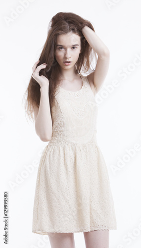 Portrait of beautiful young woman in dress with hand in her hair looking away against white background