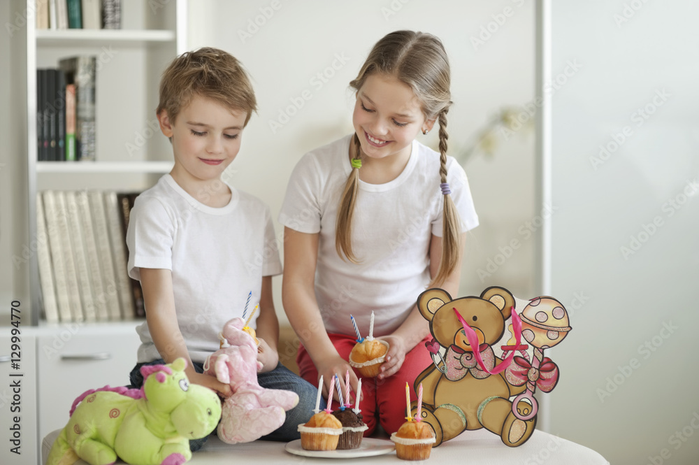 Siblings and soft toys celebrating birthday with cup cakes Siblings and soft toys celebrating birthday with cup cakes