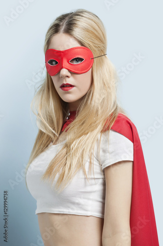 Portrait of young woman wearing superhero costume against blue background