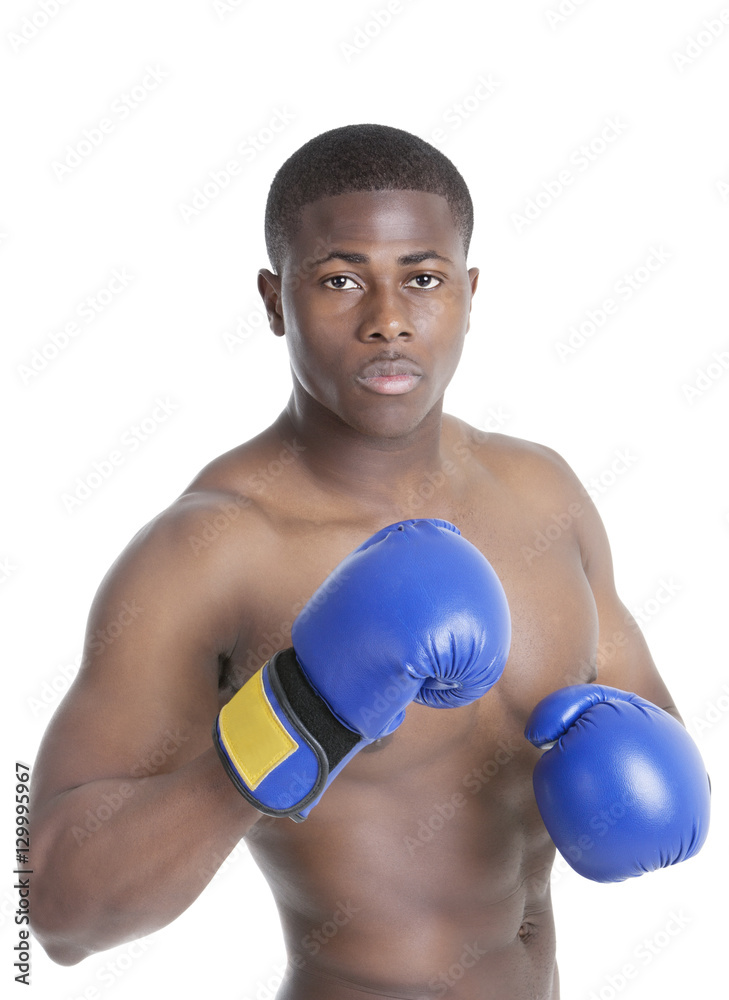 Portrait of a young boxer wearing boxing gloves in fighting stance over gray background