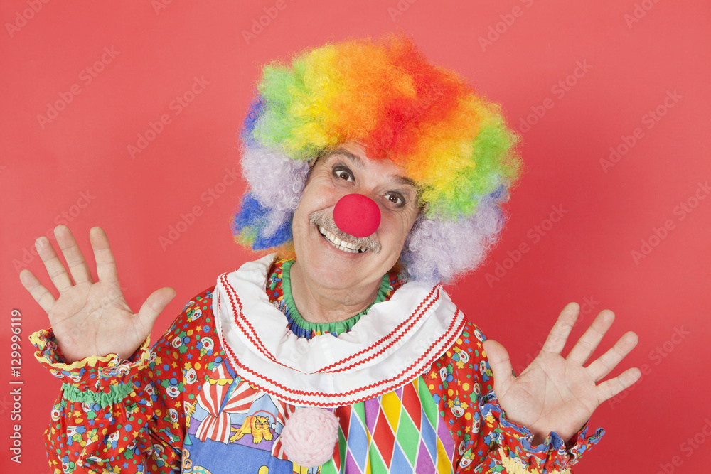 Portrait of funny clown with arms raised against colored background Portrait of funny clown with arms raised against colored background