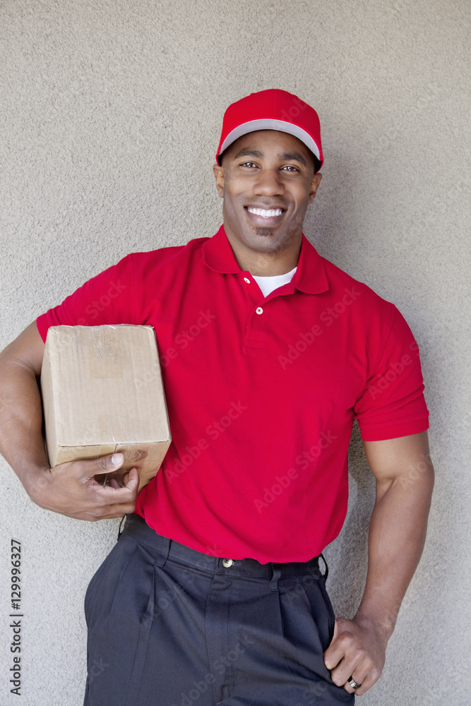 Portrait of a happy young man holding delivery box against wall Portrait of a happy young man holding delivery box against wall