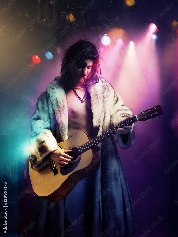 Young rock musician in fur coat playing guitar at concert Young rock musician in fur coat playing guitar at concert