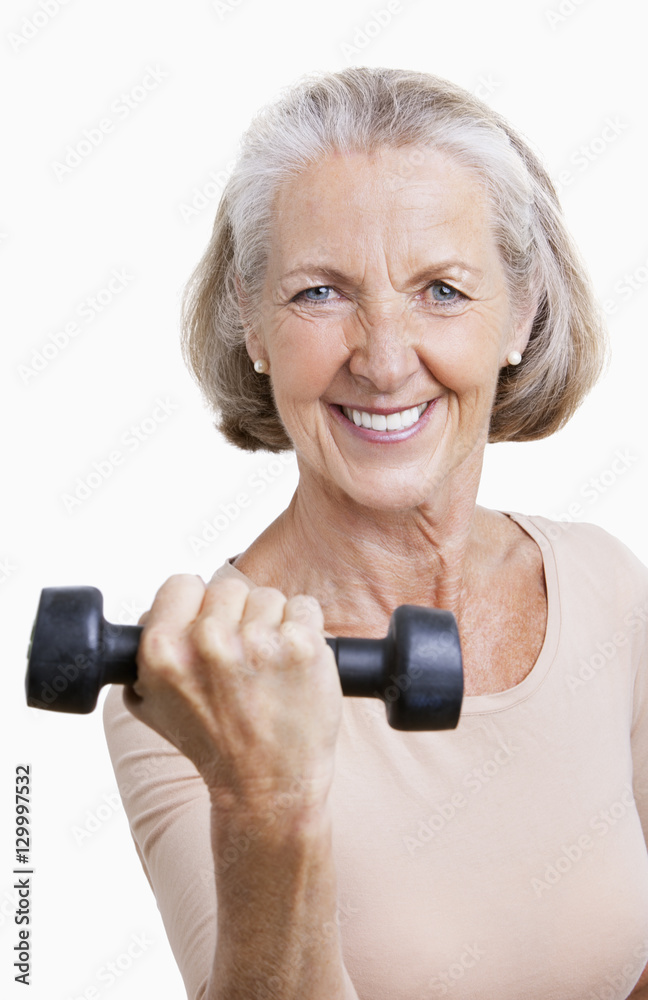 Portrait of smiling senior woman with dumbbell against white background Portrait of smiling senior woman with dumbbell against white background