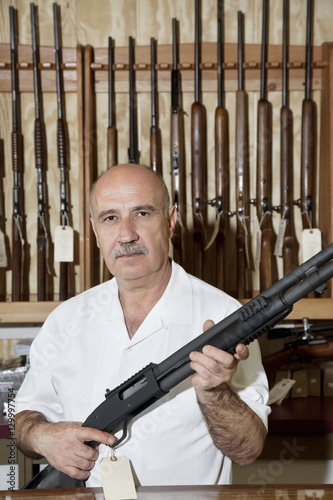 Portrait of a mature gun merchant with rifle