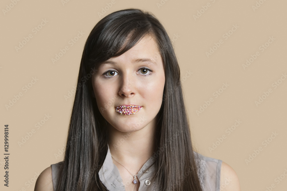 Portrait of a beautiful young woman with sprinkled lips over colored background Portrait of a beautiful young woman with sprinkled lips over colored background