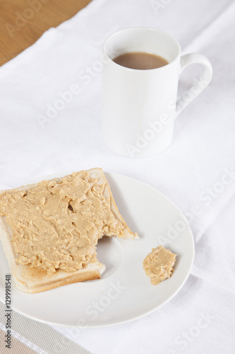 Coffee mug and peanut butter on wheat bread