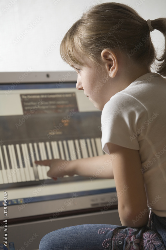Side view of girl learning keyboard on computer at home Side view of girl learning keyboard on computer at home