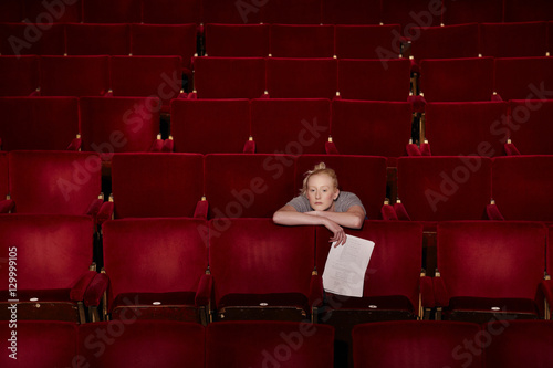 Thoughtful young woman sitting in theatre stall with script