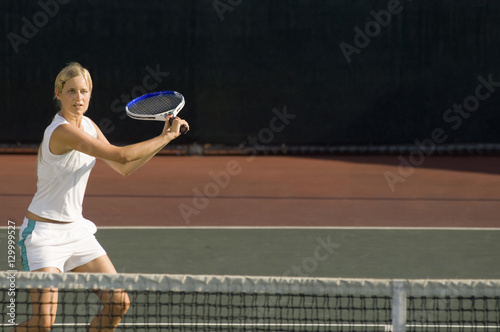 Young female tennis player swinging racket at court © moodboard