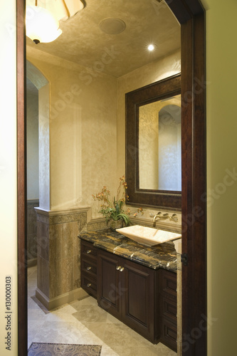 View through doorway to dark brown bathroom unit with mirror frame