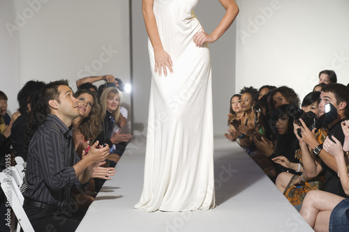 Low section of woman on fashion catwalk and audience applauding her