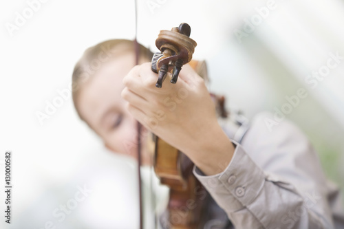 Tilt image of young girl playing violin at home