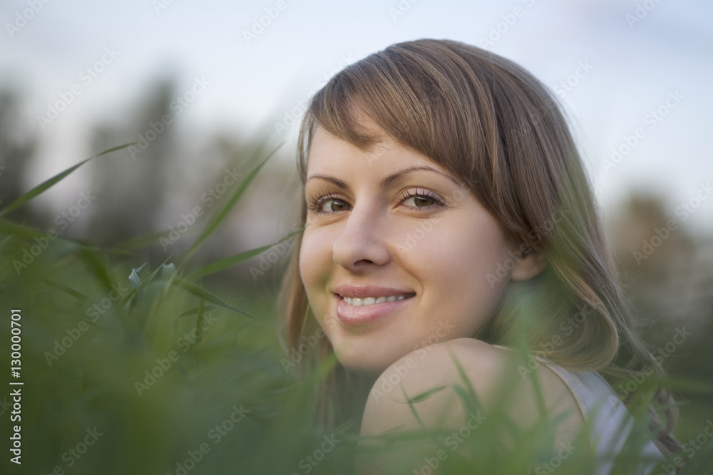 Closeup portrait of happy young woman relaxing on grass Closeup portrait of happy young woman relaxing on grass