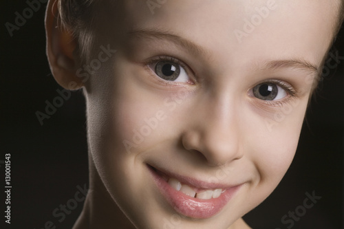 Closeup portrait of happy young girl on black background © moodboard