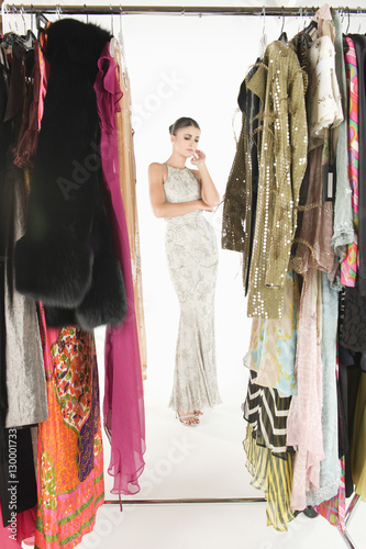 Full length view through clothing rail of a woman in long evening dress against white background © moodboard