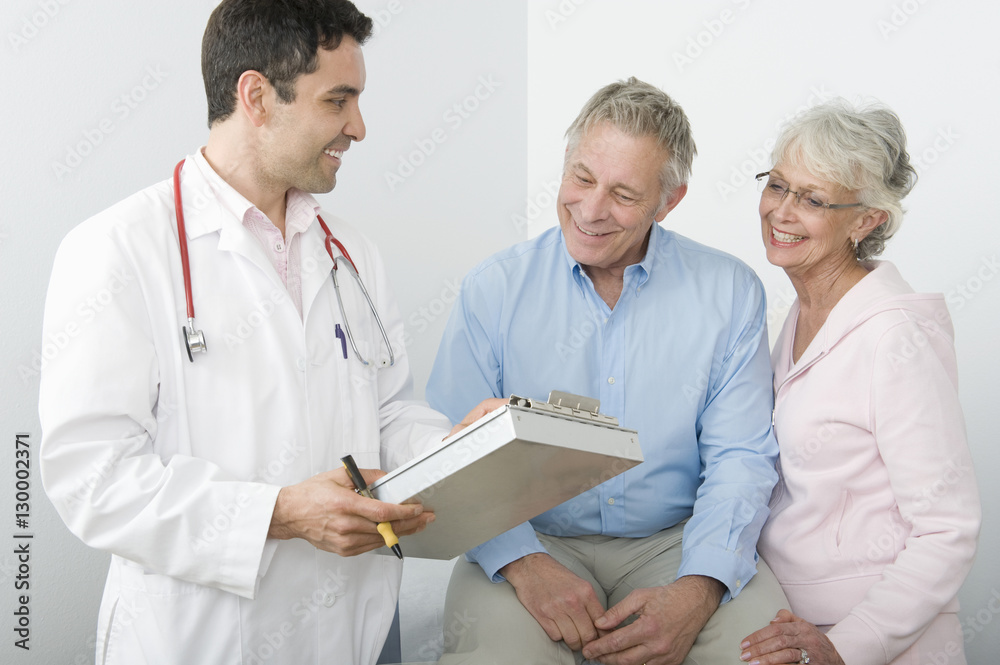 Male doctor showing reports to a senior couple in clinic Male doctor showing reports to a senior couple in clinic