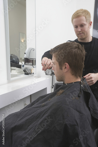 Young man getting an haircut from hairdresser in hair salon