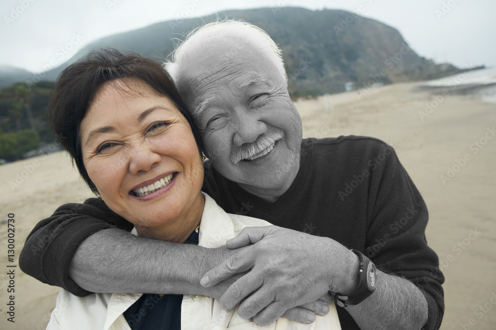 Portrait of happy senior man with his arms around middle-aged woman at beach Portrait of happy senior man with his arms around middle-aged woman at beach
