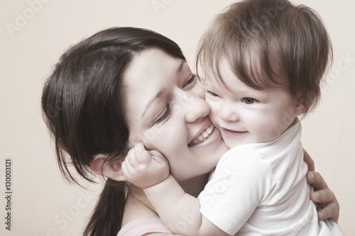Closeup of happy mother hugging baby girl over colored background