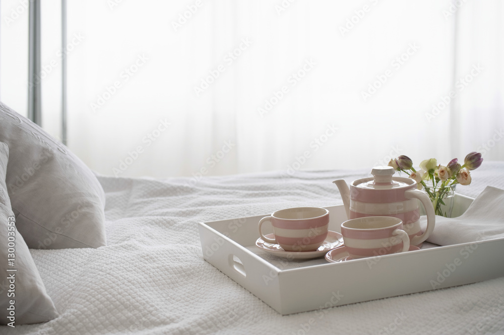 Pink striped teaset on breakfast tray in bedroom