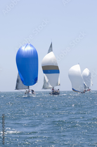 Overview of sailboats racing in the blue and calm ocean against sky