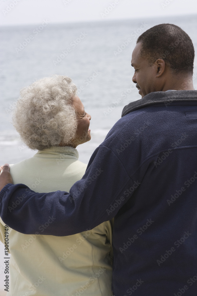 Happy African American couple looking at each other by water's edge Happy African American couple looking at each other by water's edge