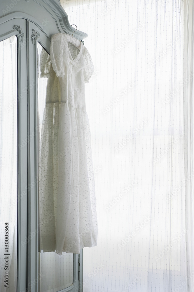 Christening gown on wardrobe at window with net curtains Christening gown on wardrobe at window with net curtains