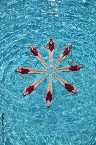 Group of synchronised swimmers forming a circle in pool