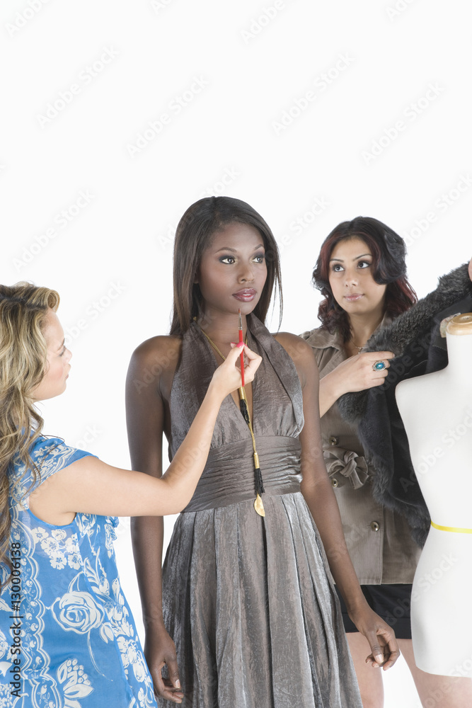 Model with two fashion stylist assisting her isolated over white background Model with two fashion stylist assisting her isolated over white background