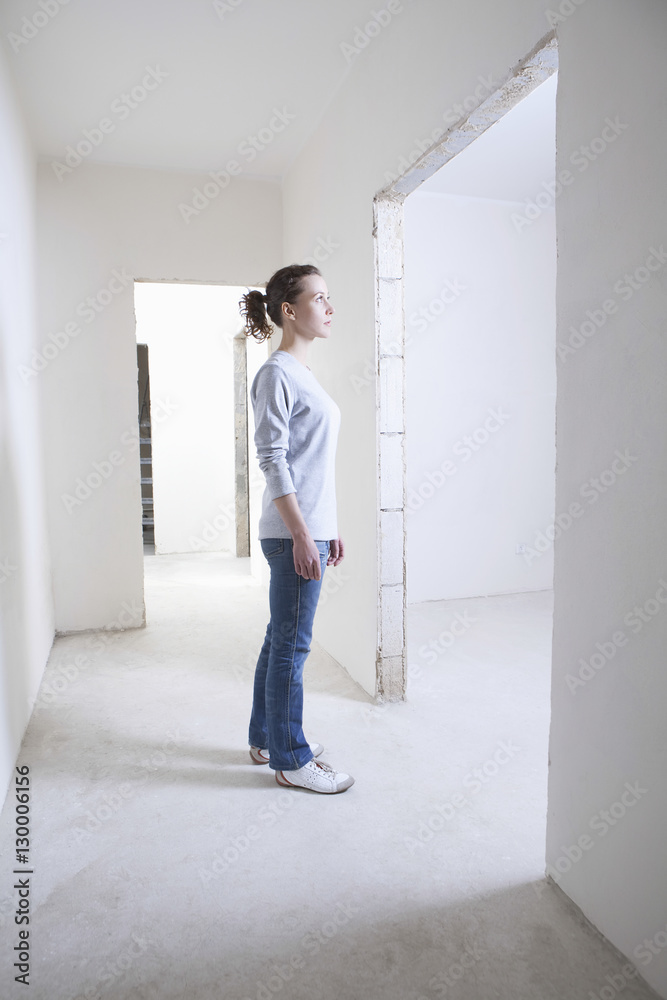 Full length side view of young woman standing in hallway of new apartment