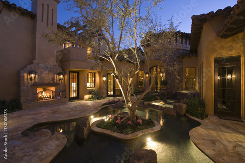 Paved courtyard with pond in lit house against clear sky photo