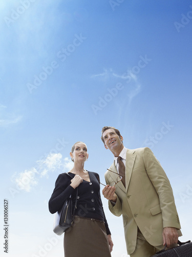 Business man and woman standing against blue sky