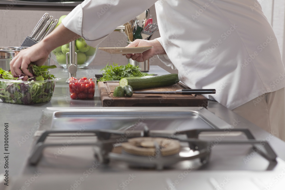 Midsection side view of male chef preparing salad in commercial kitchen Midsection side view of male chef preparing salad in commercial kitchen