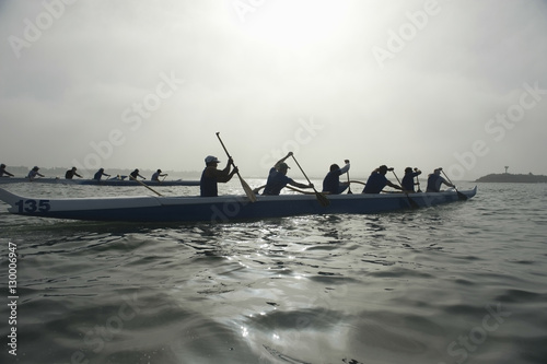 Group of multiethnic people paddling outrigger canoes in race © moodboard