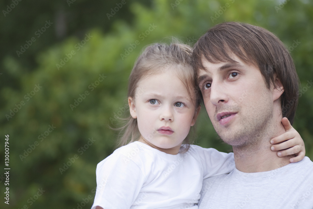 Closeup of father and daughter arm around looking away in park Closeup of father and daughter arm around looking away in park