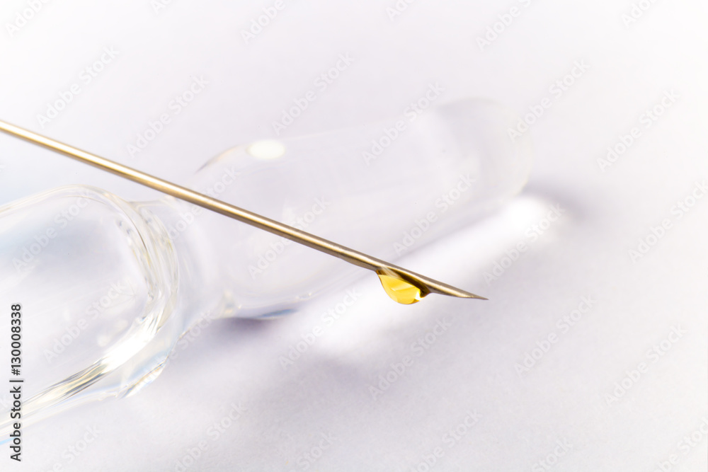 Syringe needle with drop of yellow vaccine lying on ampule with liquid drug. White background, shadows.
Syringe needle with drop of yellow vaccine lying on ampule with liquid drug. White background, shadows.
