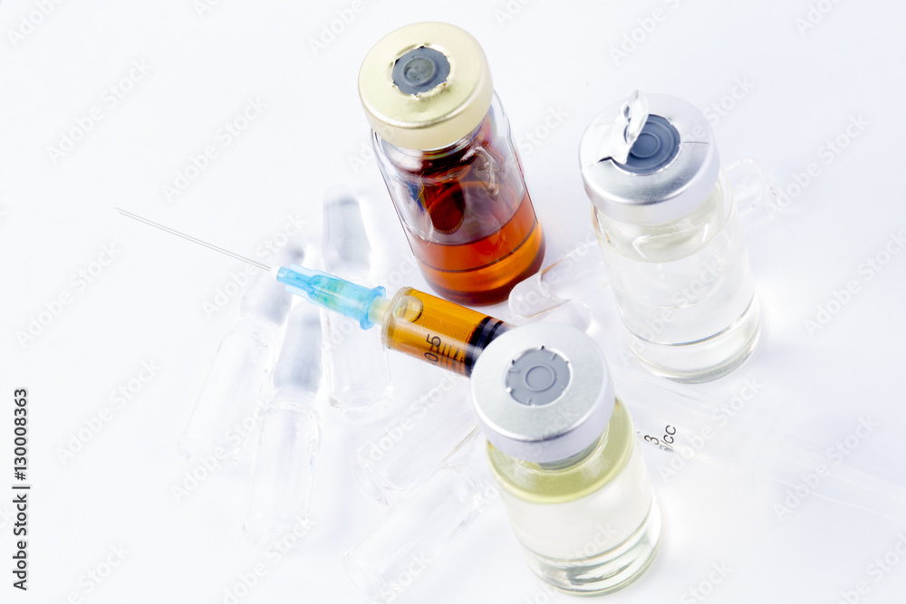 Medical syringe with brown medication lying on three glass ampules. Near three medical bottles with medicine. Two ampules with slightly yellow drug, one with brown. White background, shadows.
Medical syringe with brown medication lying on three glass ampules. Near three medical bottles with medicine. Two ampules with slightly yellow drug, one with brown. White background, shadows.