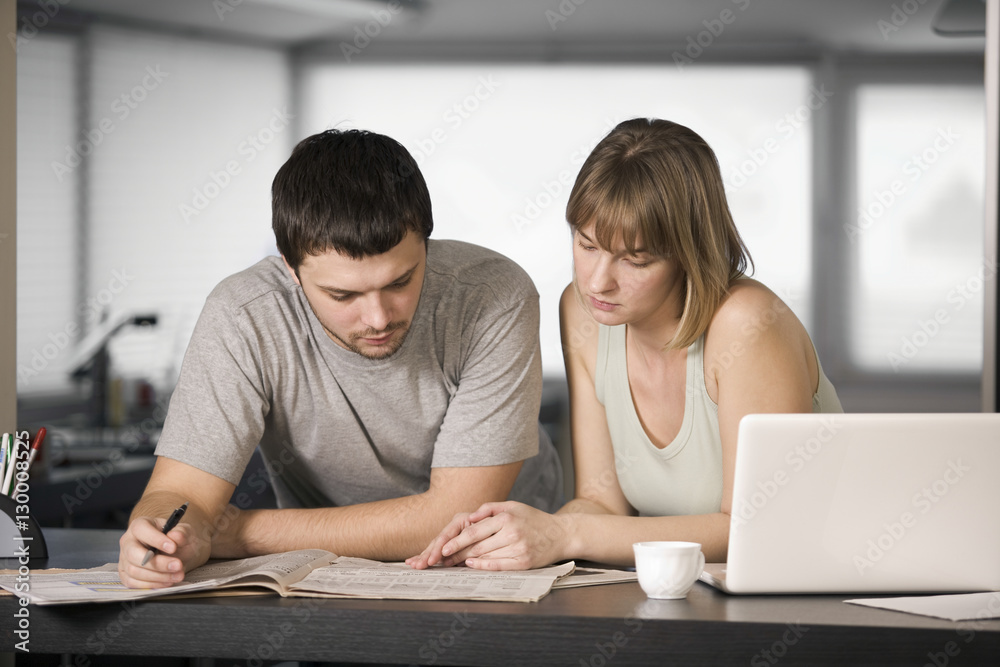 Young couple reading newspaper together at counter Young couple reading newspaper together at counter