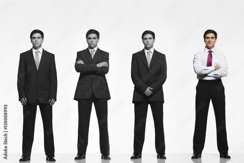 Portrait of mid-adult businessman standing out from a line coworkers against white background