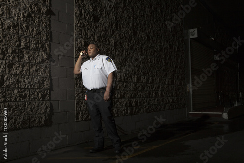 Young male security guard in uniform patrols at night with torch © moodboard