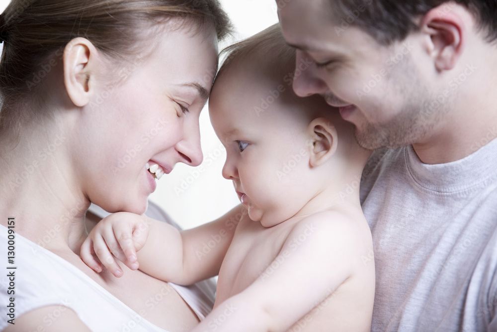 Closeup side view of happy young family with their little son on white background Closeup side view of happy young family with their little son on white background