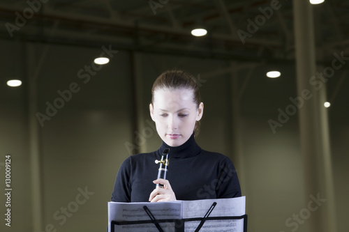 Beautiful clarinet player looking at music sheet under spotlights photo