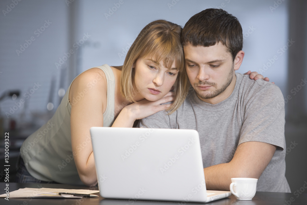 Young couple using laptop at desk in house