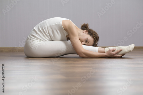 Portrait of woman doing stretching exercise on hardwood floor at home